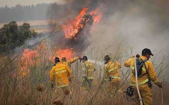 Firefighters try to extinguish a brush fire near Moshav Aderet, July 17, 2019. (Noam Revkin Fenton/Flash90)