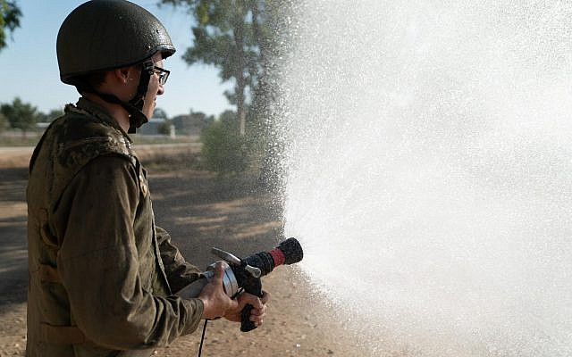 An Israeli soldier uses a fire hose in an undated photograph. (Israel Defense Forces)