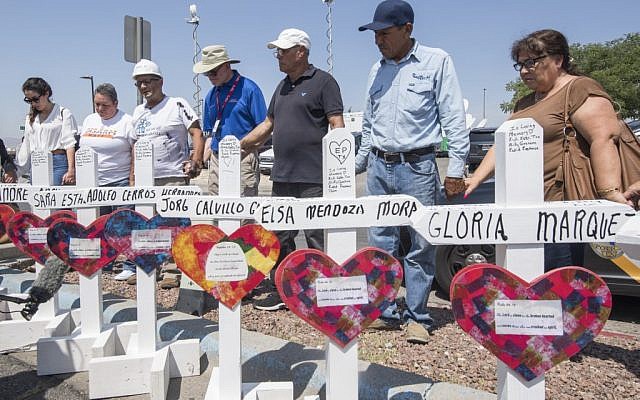 People pray beside crosses with the names of victims who died in the shooting to a makeshift memorial after the shooting that left 22 people dead at the Cielo Vista Mall WalMart in El Paso, Texas, on August 5, 2019. (Mark Ralston/AFP)