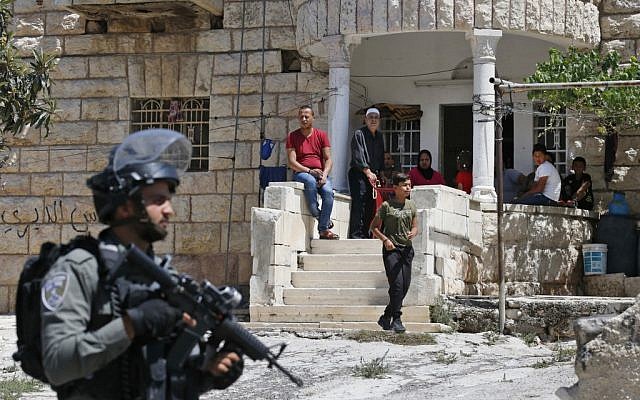 Palestinians look on as Israeli soldiers take part in a house-to-house search operation in the West Bank village of Beit Fajjar near Bethlehem on August 8, 2019, following a stabbing attack. (HAZEM BADER / AFP)