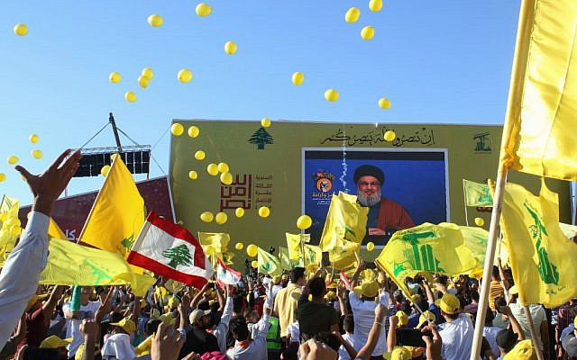 Supporters of the Hezbollah terror group wave the group's flag during a commemoration marking the 13th anniversary of the end of the 2006 war with Israel in the southern Lebanese town of Bint Jbeil on August 16, 2019. (Mahmoud Zayyat/AFP)