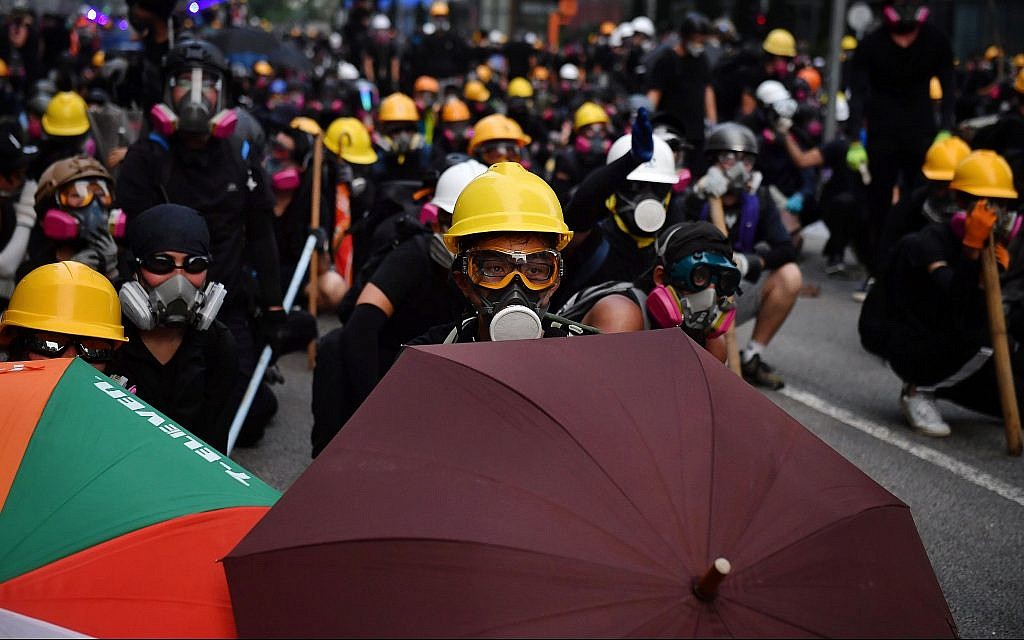 Protesters with umbrellas and protective gear face off with riot police at Kowloon Bay in Hong Kong, August 24, 2019. (Lillian Suwanrumpha/AFP/Getty Images/via JTA)