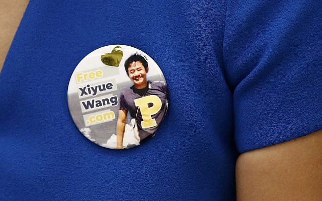 Hua Qu, the wife of Xiyue Wang, a Princeton University graduate student being held at an Iranian prison, wears a button bearing a picture of her husband as she speaks at a news conference to mark the third anniversary of his imprisonment, August 8, 2019, at the National Press Club in Washington. (AP Photo/Patrick Semansky)