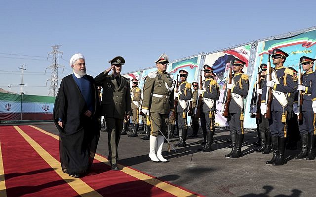 In this photo released by the official website of the office of the Iranian Presidency, President Hassan Rouhani, left, reviews an honor guard as he is accompanied by his Defense Minister Gen. Amir Hatami during a ceremony to unveil Iran-made Bavar-373 air-defense missile system, Iran, Thursday, Aug. 22, 2019. (Iranian Presidency Office via AP)