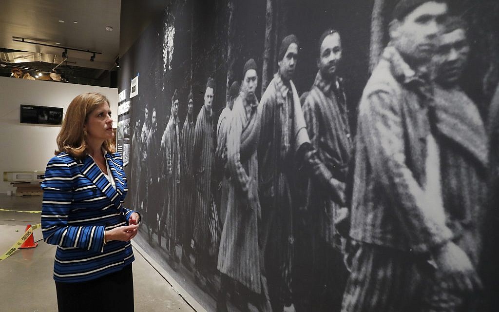 In this July 29, 2019, photo, Dallas Holocaust and Human Rights Museum President and CEO, Mary Pat Higgins, pauses as she gives a tour of the museum in Dallas, to look at a wall size image of Jews marching. When Dallas’ Holocaust museum reopens in a few weeks it will not only be in a new building five times the size of its previous location, but will take visitors on a journey that also includes modern-day genocides and the evolution of human and civil rights in the U.S. (AP Photo/Tony Gutierrez)
