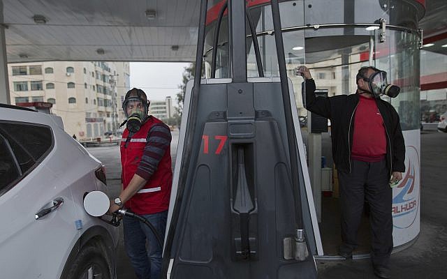 Two Palestinian gas station workers wear teargas masks while supplying vehicles with gasoline during clashes following protests against US President Donald Trump's decision to recognize Jerusalem as the capital of Israel, in the West Bank city of Ramallah, Thursday, Dec. 21, 2017. (AP/Nasser Nasser)