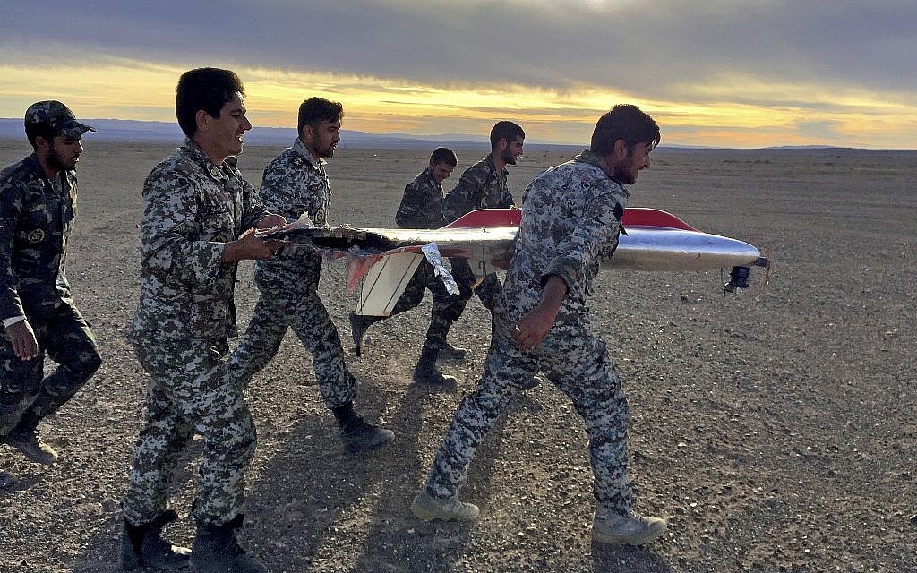 In this photo provided by the Iranian Army Monday, Nov. 5, 2018, soldiers carry the wreckage of a drone during drills in Semnan, Iran. (Iranian Army via AP)
