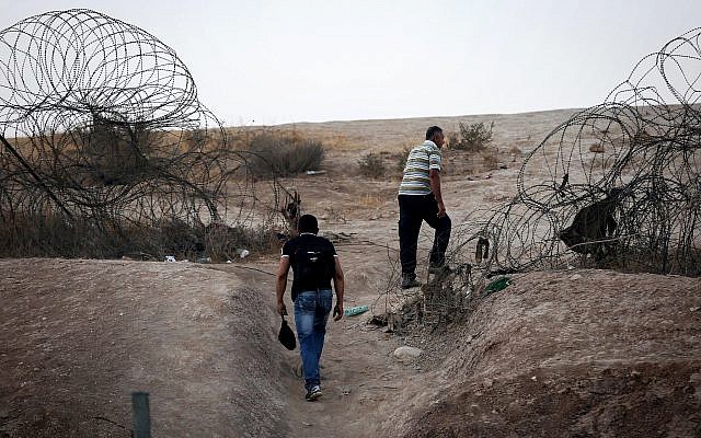 Palestinians illegally crossing the Israeli security fence through a hole to enter Israel on the outskirts of the West Bank city of Hebron, on August 6, 2019. (Wisam Hashlamoun/Flash90)