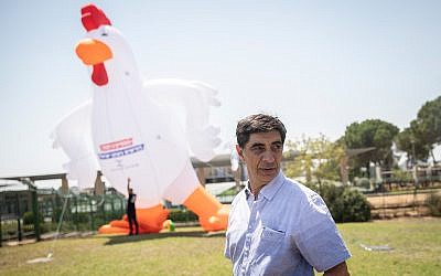 Simcha Goldin, the father of slain IDF soldier Hadar Goldin, stands with a 10 meter (32 foot) tall inflatable rooster at a demonstration outside the Knesset on August 14, 2019. (Hadas Parush/Flash90)