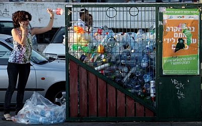 A woman throws a bottle into a recycling bin in Jerusalem. (Nati Shohat/Flash90)