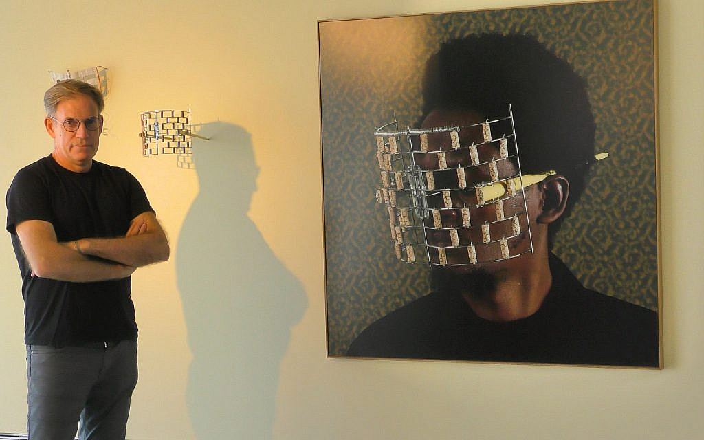 Tel Aviv Art dealer Serge Tiroche in front of a photo of Cyrus Kabiru donning the 'Famous Wall' eyeglasses. (Bernard Dichek/ Times of Israel)