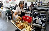 A Lasova restaurant soup kitchen employee serves bread to the needy in Tel Aviv on September 8, 2019. (Menahem Kahana/AFP)