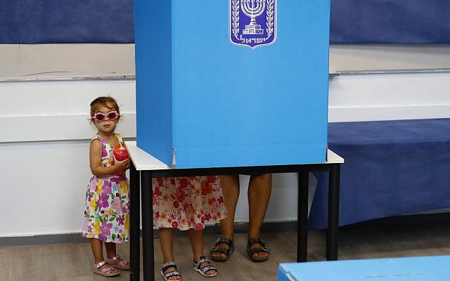 Israeli children accompany their father in a polling booth during Knesset elections at a polling station in Rosh Ha'ayin, on September 17, 2019. (Jack Guez/AFP)