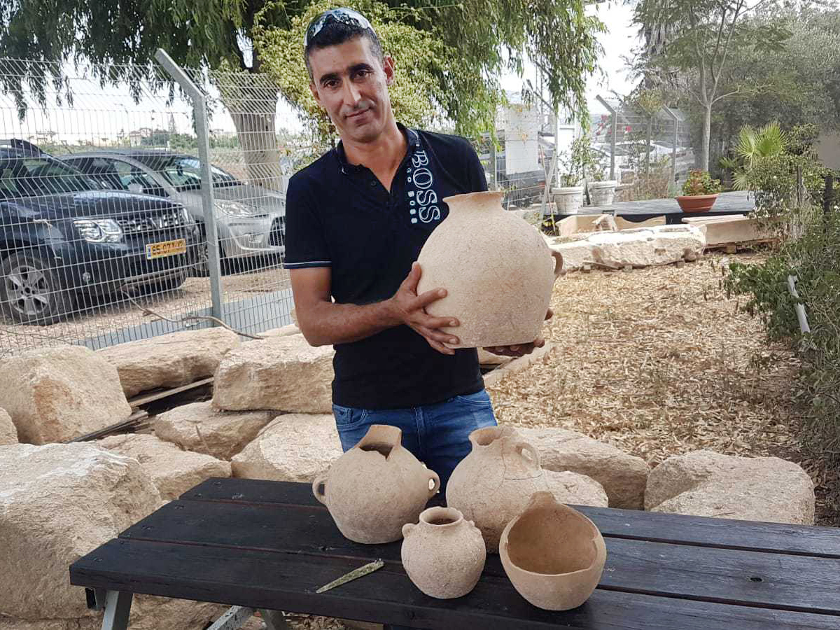 Ahmed Nassar Yassin with 4,500-year-old artifacts he discovered in a burial cave near Araba in northern Israel. (Nir Distelfeld/Israel Antiquities Authority)