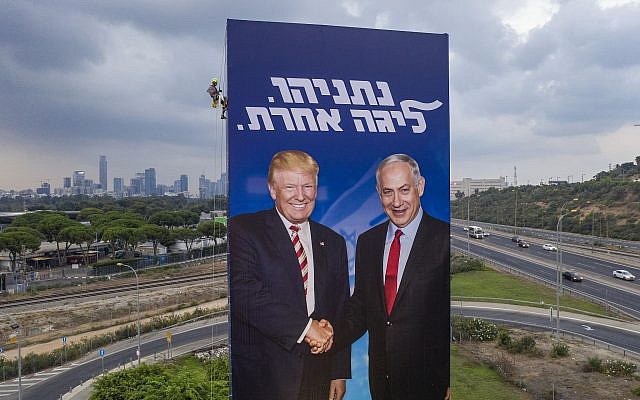 A worker hangs an election campaign billboard of the Likud party shows Prime Minister Benjamin Netanyahu, right, and US President Donald Trump in Tel Aviv, Israel  on September 8, 2019. Hebrew on billboard reads 'Netanyahu, in another league.' (AP/Oded Balilty)