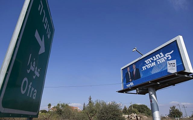 An election campaign billboard for the Likud party shows Prime Minister Benjamin Netanyahu and US  President Donald Trump, facing a road sign directing traffic to the West Bank Israeli settlement of Ofra, north of Ramallah, September 11, 2019 (AP Photo/Nasser Nasser)