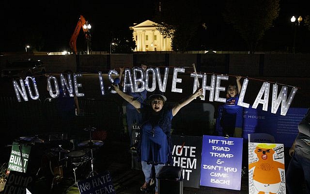 Protesters with Kremlin Annex with a light sign that reads “NO ONE IS ABOVE THE LAW” call to impeach US President Donald Trump in Lafayette Square Park in front of the White House in Washington on September 26, 2019. (AP/Carolyn Kaster)