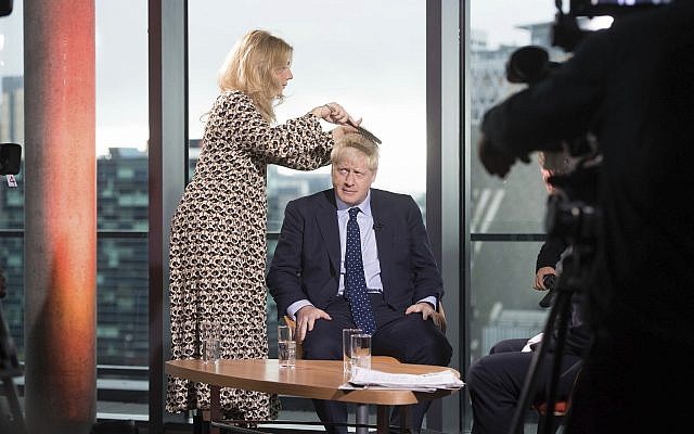 British Prime Minister Boris Johnson has his hair combed as he prepares to appear on a TV political show at Media City in Salford, England, before opening the Conservative party annual conference on September 29, 2019. (Stefan Rousseau/PA via AP)