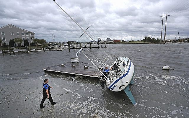 Beaufort Police Officer Curtis Resor, left, and Sgt. Micheal Stepehens check a sailboat for occupants in Beaufort, N.C. after Hurricane Dorian passed the North Carolina coast on Friday, Sept. 6, 2019. (AP Photo/Tom Copeland)
