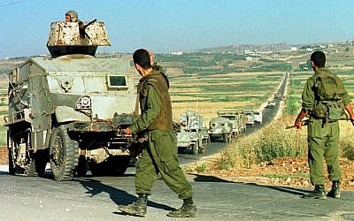 Two militiamen of the Israeli-backed South Lebanon Army direct a convoy of armored vehicles in southern Lebanon, June 3, 1999. (Butros Wanna/AP)