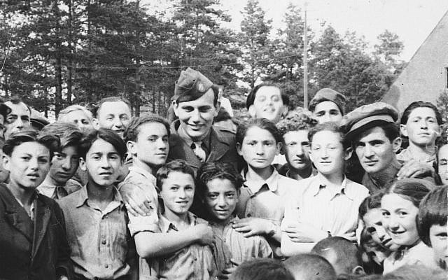 Illustrative: Children at the Foehrenwald DP camp gather around a US soldier. (United States Holocaust Memorial Museum, courtesy of Larry Rosenbach)
