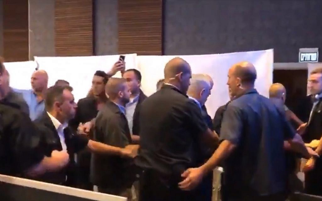 Prime Minister Benjamin Netanyahu, center, being moved away from a campaign event stage while surrounded by security as rockets are shot at Ashdod on September 10, 2019. (screen capture: Twitter)