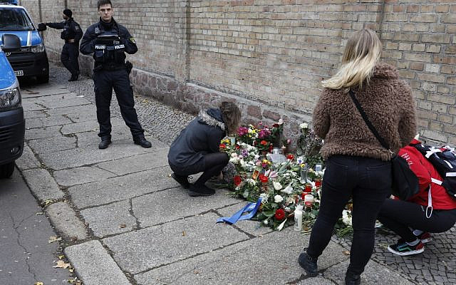 People place flowers at a makeshift memorial in front of the synagogue in Halle, eastern Germany, on October 10, 2019, one day after the attack where two people were shot dead. (Axel Schmidt/AFP)