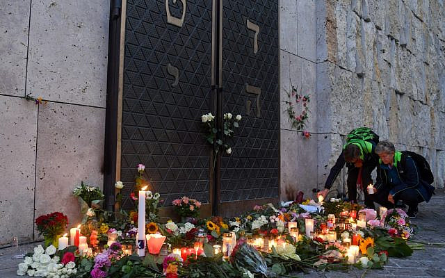 Two women light candles among others and flowers next to the entrance of the synagogue in Munich, during a protest against anti-Semitism on October 11, 2019 two days after a deadly shooting outside a synagogue in Halle. (Photo by Christof STACHE / AFP)