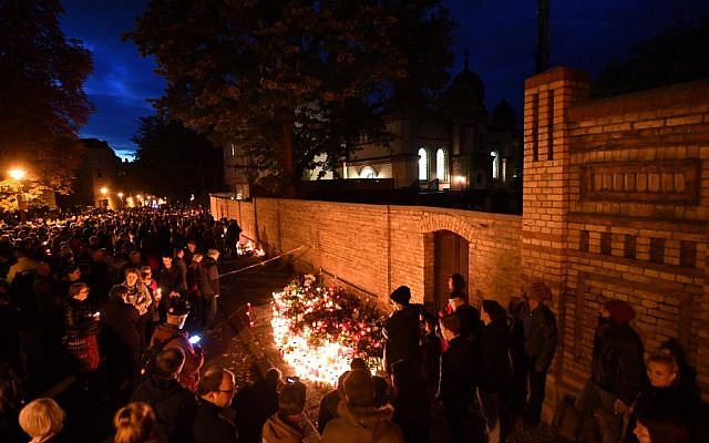 Mourners stand around a makeshift memorial of candles and flowers at the synagogue in Halle, eastern Germany, on October 11, 2019, two days after a deadly shooting. (Photo by Hendrik Schmidt / dpa / AFP) / Germany OUT
