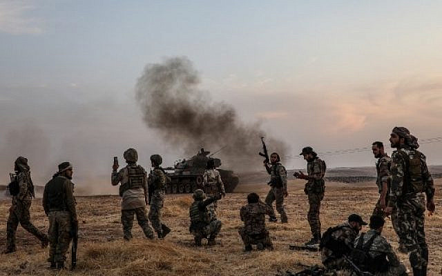 In this file photo taken on October 14, 2019 Turkish soldiers and Turkey-backed Syrian fighters gather on the northern outskirts of the Syrian city of Manbij near the Turkish border as Turkey and its allies continue their assault on Kurdish-held border towns in northeastern Syria. (Photo by Zein Al RIFAI / AFP)