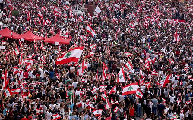 Lebanese demonstrators wave national flags as they take part in a rally in the capital Beirut's downtown district on October 20, 2019. (Patrick Baz/AFP)
