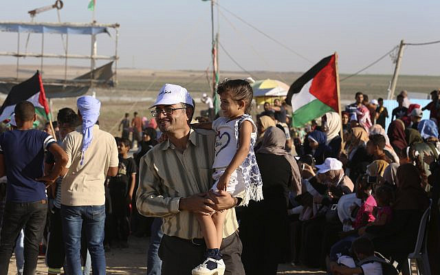 In this Sept. 25, 2019 photo, Palestinian activist Ahmed Abu Artima holds his daughter during an alternative protest he organized near the separation fence between the Gaza Strip and Israel, east of Gaza City. (AP Photo/Adel Hana)