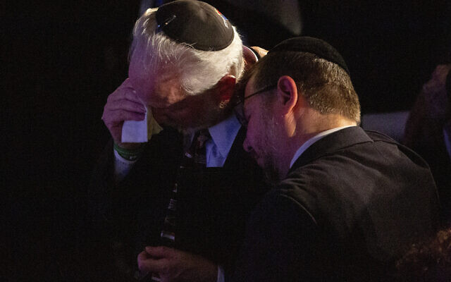 Rabbi Jeffrey Myers, center, of the Tree of Life/Or L'Simcha Congregation, is comforted after saying a prayer for the souls of the deceased during the one-year commemoration of the Tree of Life synagogue attack, at Soldiers & Sailors Memorial Hall and Museum, Sunday, Oct. 27, 2019, in Pittsburgh. (AP Photo/Rebecca Droke)