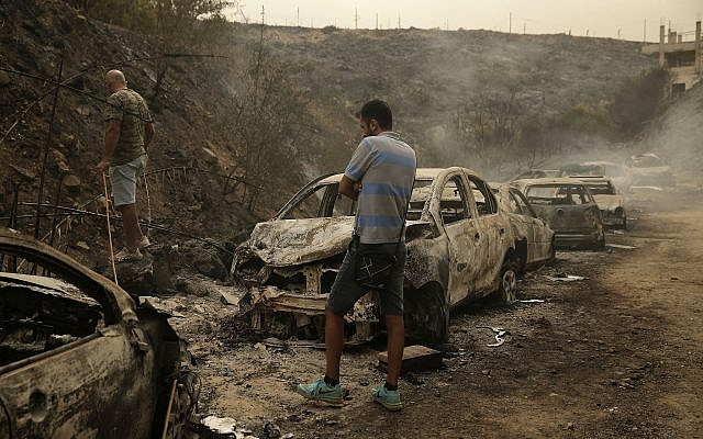 People inspect the remains of cars and shops that were burned in a wildfire overnight, in the town of Damour just over 15 kilometers south of Beirut, Lebanon, on October 15, 2019. (AP Photo/Hassan Ammar)