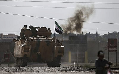 Turkish-backed Syrian opposition fighters on an armoured personnel carrier drive to cross the border into Syria, in Akcakale, Sanliurfa province, southeastern Turkey, October 18, 2019. (AP Photo/Emrah Gurel)