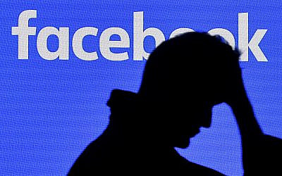 Illustrative: A man passes a Facebook screen at the Gamescom gathering in Cologne, Germany, August 20, 2019. (AP Photo/Martin Meissner)