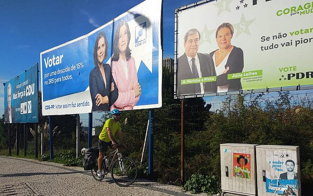 רוכב אופניים עובר בשלטים למפלגות פוליטיות בפורטוגל במהלך הבחירות הלאומיות בפורטו, פורטוגל, ב -6 באוקטובר 2019. (מלאני לידמן / טיימס ישראל)