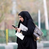 A woman uses a smartphone while standing on a street in the Iranian capital Tehran on November 23, 2019. (ATTA KENARE/AFP)