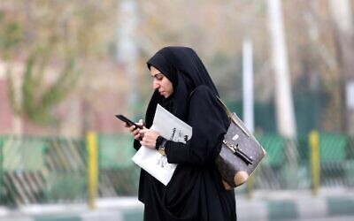 A woman uses a smartphone while standing on a street in the Iranian capital Tehran on November 23, 2019. (ATTA KENARE/AFP)