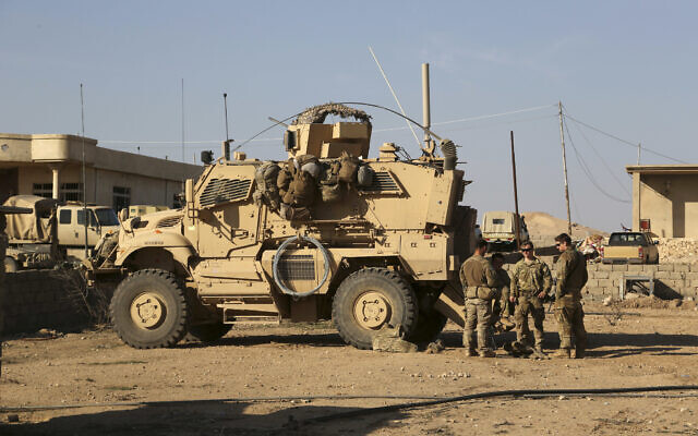 In this photo from February 23, 2017, US Army soldiers stand outside their armored vehicle on a joint base with Iraqi army south of Mosul, Iraq. (AP Photo/Khalid Mohammed, File)