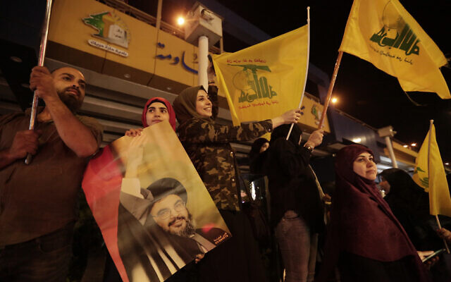 In this October 25, 2019 file photo, supporters of Hezbollah leader Hassan Nasrallah hold pictures and wave Hezbollah flags in a southern suburb of Beirut, Lebanon. (AP Photo/Hassan Ammar, File)
