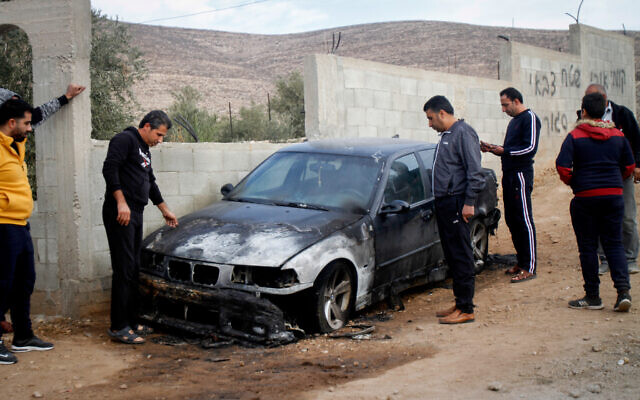 Illustrative: Palestinian men inspect a car that was burnt in a suspected hate crime in the northern West Bank village of Beit Dajan on November 22, 2019. (Nasser Ishtayeh/Flash90)