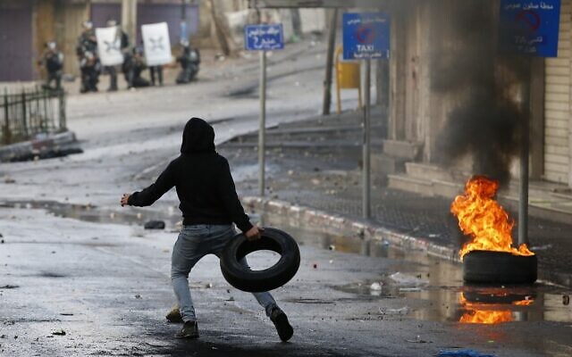 A Palestinian protester throws a tire during clashes with Israeli security forces in the southern West Bank city of Hebron, on December 9, 2019, amid a general strike over Israeli settlement activity. (HAZEM BADER / AFP)