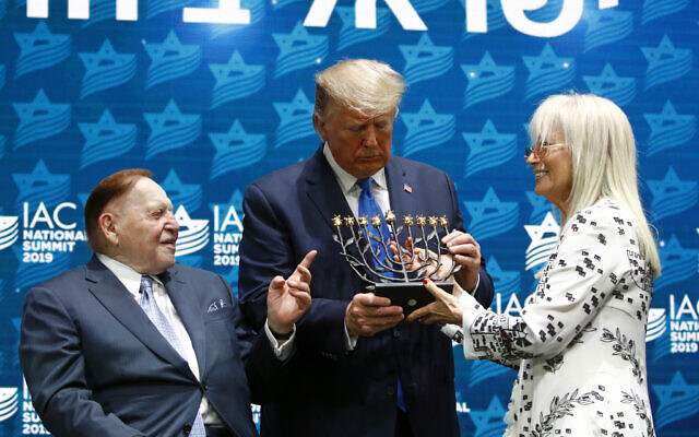 President Donald Trump receives a menorah from Las Vegas Sands Corporation Chief Executive and Republican mega donor Sheldon Adelson, left, and his wife Miriam Adelson at the Israeli American Council National Summit in Hollywood, Fla., Saturday, December 7, 2019. (AP/Patrick Semansky)