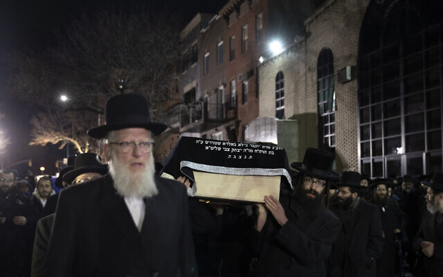 Orthodox Jewish men carry the casket with Mindel Ferencz outside a Brooklyn synagogue, Wednesday, Dec. 11, 2019, in New York. Her funeral will be in Jersey City. Ferencz was killed Tuesday in the shooting inside a Jersey City, N.J., food market. (AP Photo/Mark Lennihan)