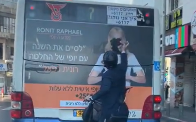 An ultra-Orthodox man vandalizing a campaign ad on a bus by tearing off the face of a woman from a poster, in footage published on December 8, 2019. (Screenshot: Twitter)
