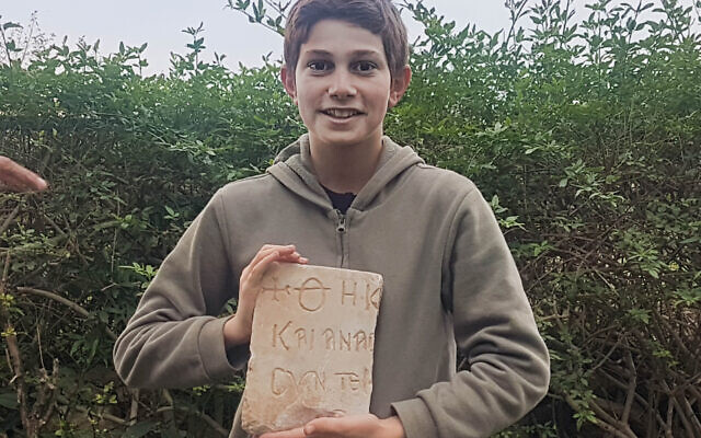 Stav Meir, 13, holding a 1,500-year-old Greek burial inscription that he discovered near Caesarea. (Karem Said/ Israel Antiquities Authority)