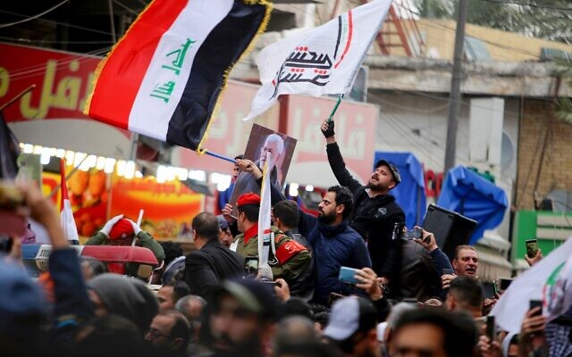 Mourners wave the national flag and the Hashed al-Shaabi flag as they carry the portrait Iraqi paramilitary chief Abu Mahdi al-Muhandis during a funeral procession, for Muhandis and Iranian military commander Qasem Soleimani, in Kadhimiya, a Shiite pilgrimage district of Baghdad, on January 4, 2020 (SABAH ARAR / AFP)