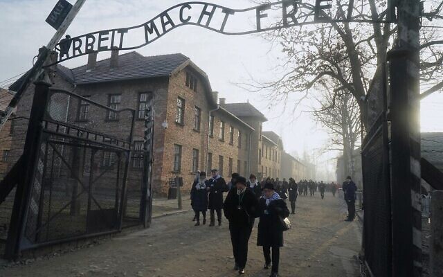 Holocaust survivors walk below the gate with its inscription 'Work sets you free' after a wreath laying at the death wall at the memorial site of the former Nazi death camp Auschwitz during ceremonies to commemorate the 75th anniversary of the camp's liberation in Oswiecim, Poland, on January 27, 2020 (Janek Skarzynski/AFP)
