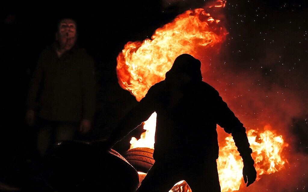Los manifestantes palestinos queman llantas durante una manifestación contra la propuesta del plan de paz del presidente de los Estados Unidos, Donald Trump, el 28 de enero de 2020, a la entrada de la ciudad cisjordana de Ramallah, cerca del asentamiento de Beit El.  (Ahmad GHARABLI / AFP)
